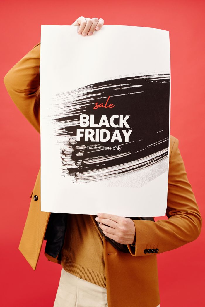 our-values Individual holding a vibrant Black Friday sale poster against a red background.
